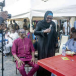 Professor Razinat Mohammed reading a poem in honour of Mama Magareth Ukah as Camillus Ukah (left) smiles
