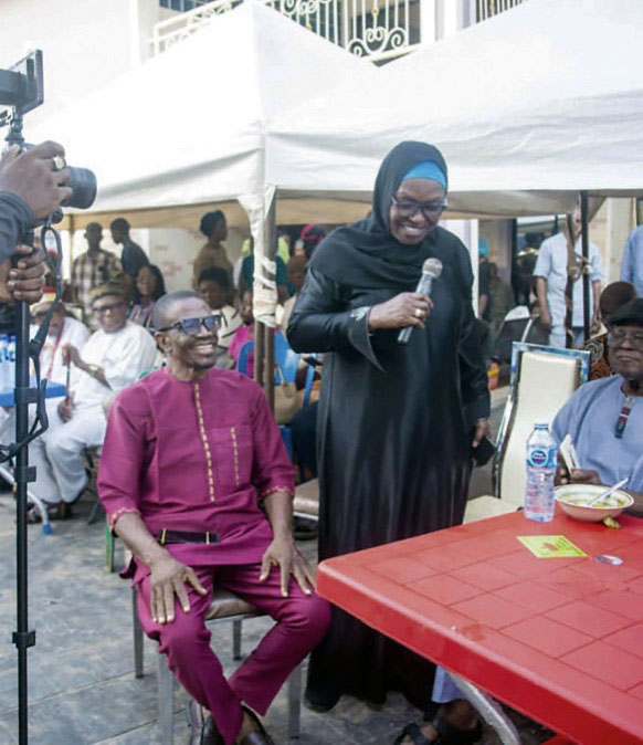 Professor Razinat Mohammed reading a poem in honour of Mama Magareth Ukah as Camillus Ukah (left) smiles